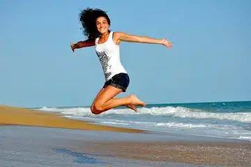 Gesunder Lebensstil erfreut Frau am Meer und daher springt sie in die Luft.